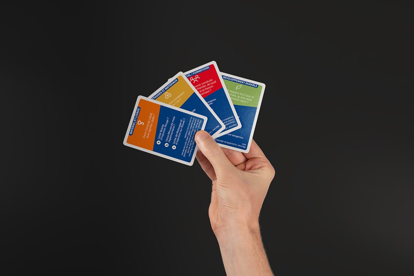 Hand holding several colourful modern branding cards by the Comhit Paris agency. Innovative graphic design.
